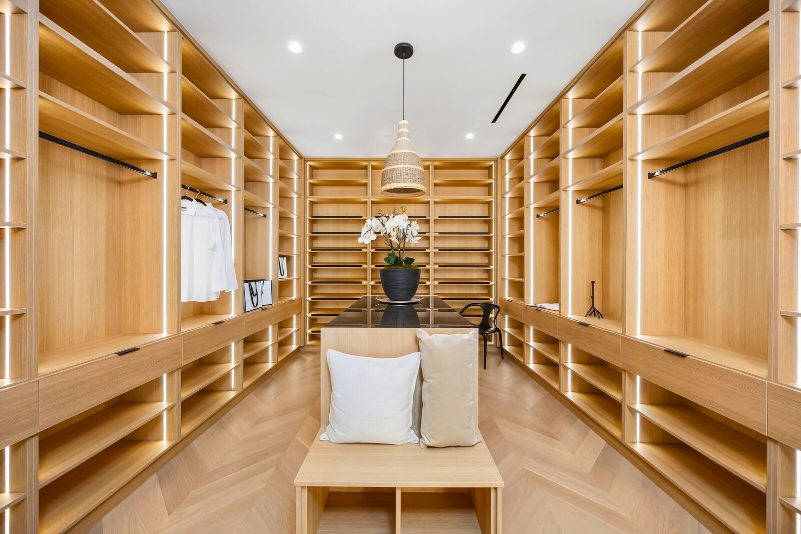 Custom walk-in closet with wood shelving and center bench in Los Angeles