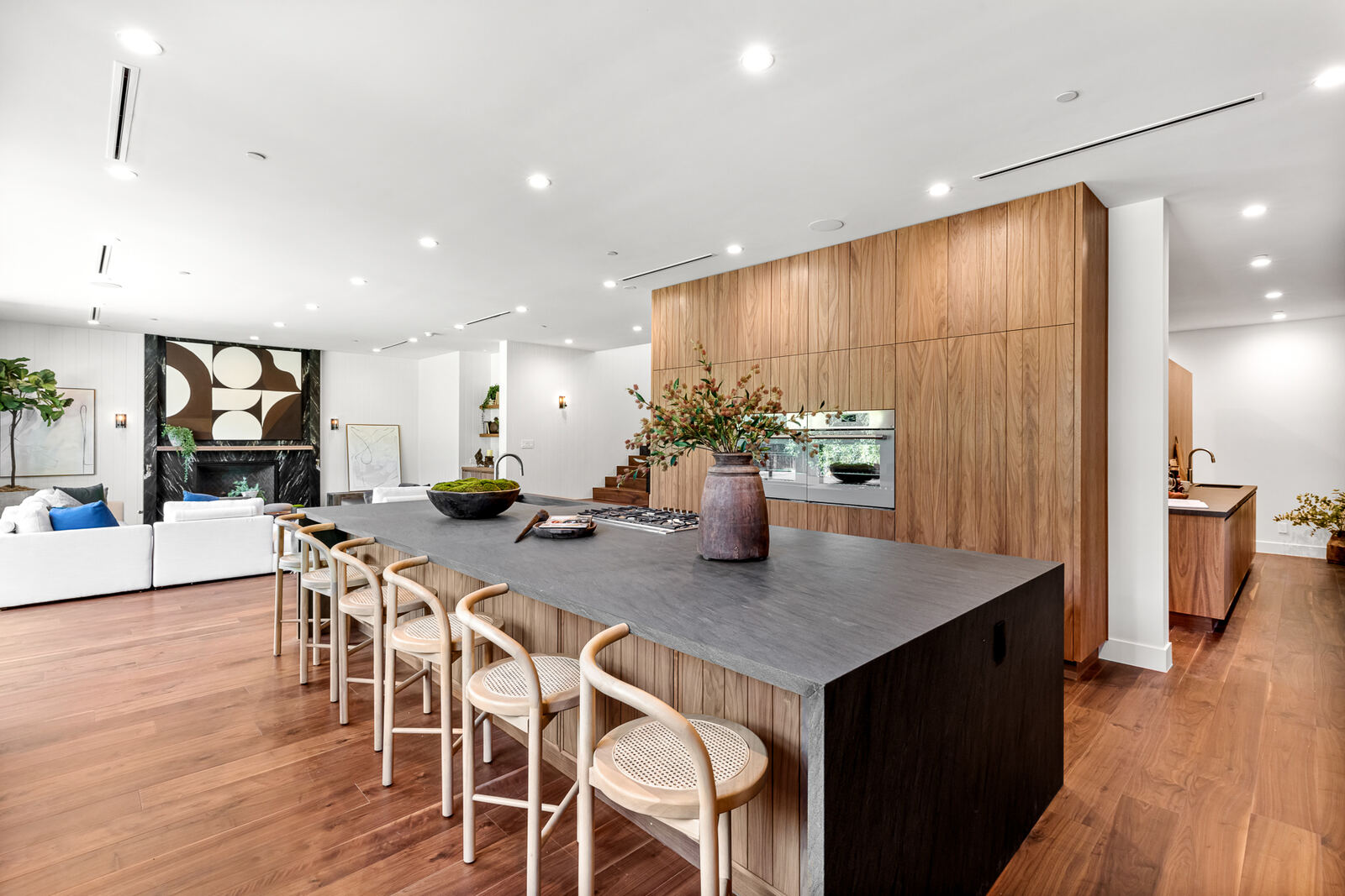 Dark kitchen island with woven bar stools and wood cabinetry in Los Angeles