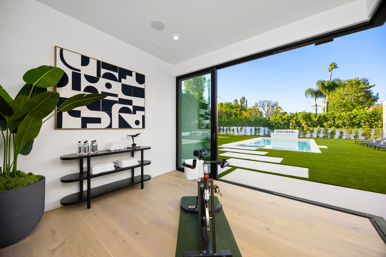 Home gym with glass doors overlooking a Los Angeles pool
