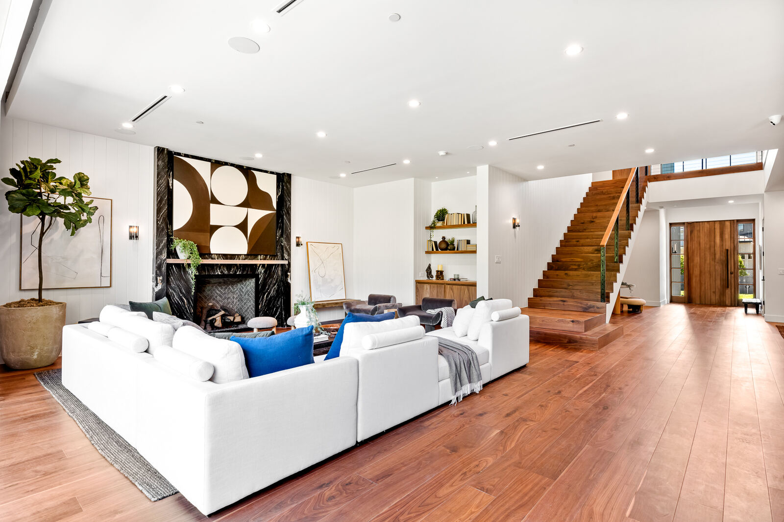 Los Angeles living room with black fireplace wall and wood staircase