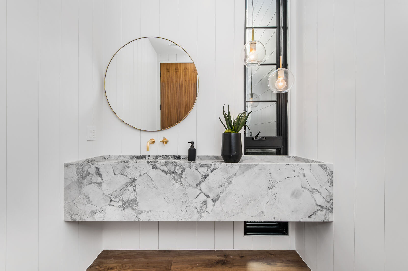 Marble vanity with round mirror in a San Fernando Valley bathroom