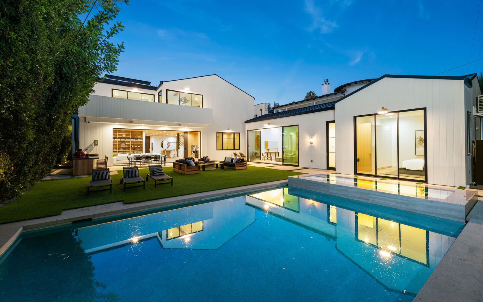 Modern Los Angeles home reflected in a backyard pool and spa