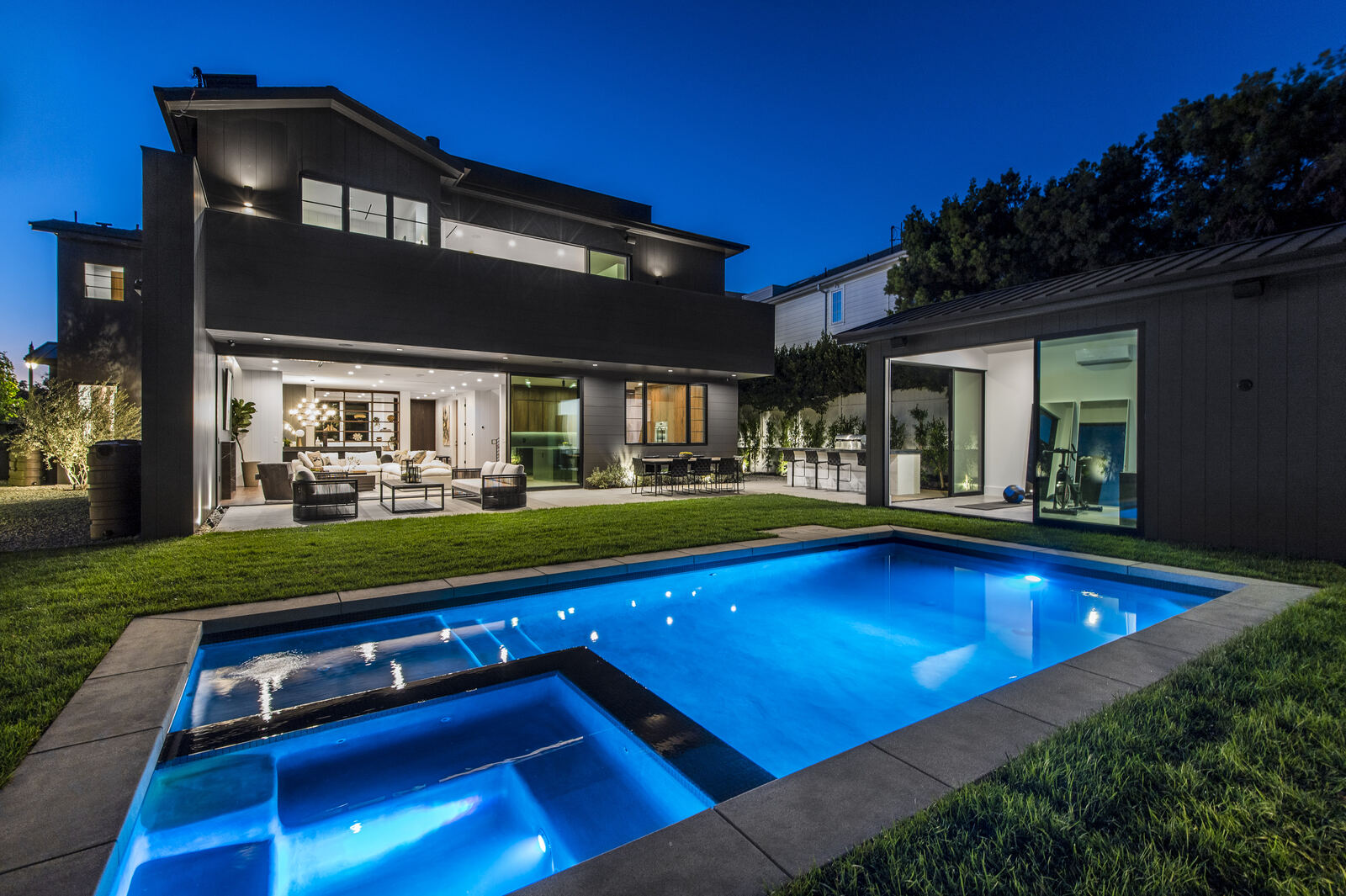 Modern Van Nuys backyard with a glowing pool and spa at night