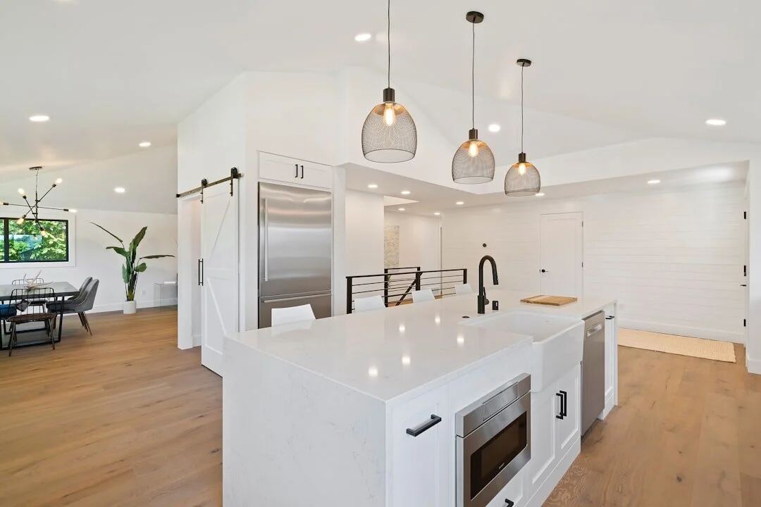 White Los Angeles kitchen with waterfall island and glass pendant lights